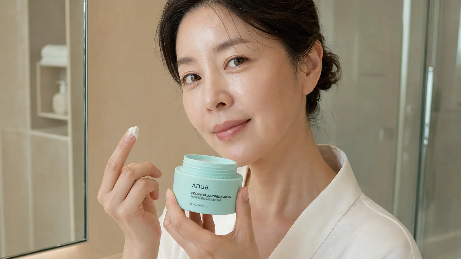 Hand scooping a small amount of the Anua PDRN cream from the jar showing its lightweight gel texture